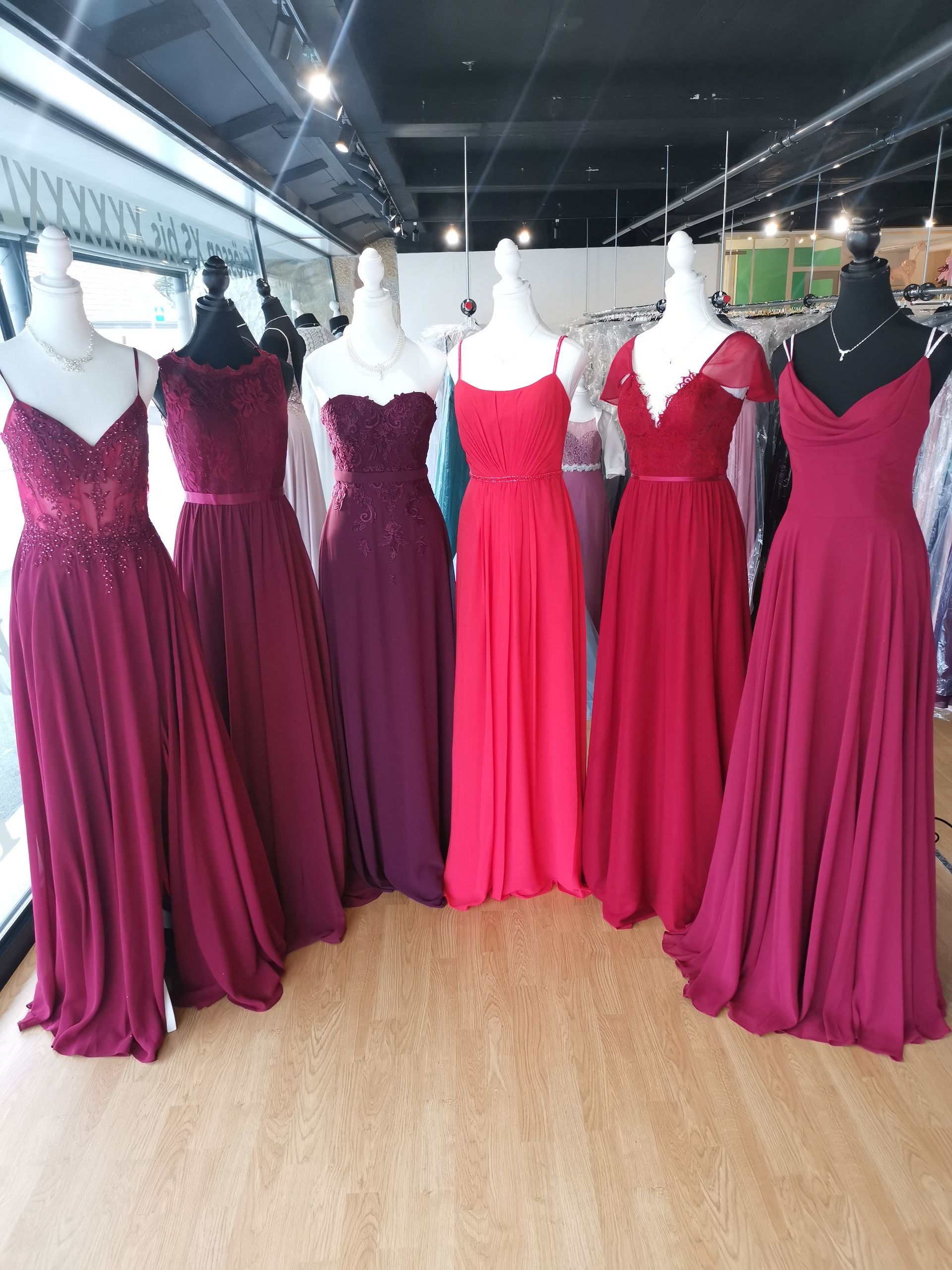 Eine Gruppe roter Kleider auf Schaufensterpuppen in einem Geschäft