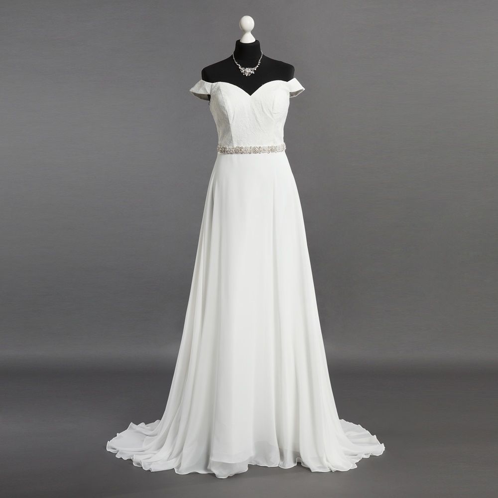 Auf einer Schaufensterpuppe hängt ein weißes Brautkleid mit einer Halskette.