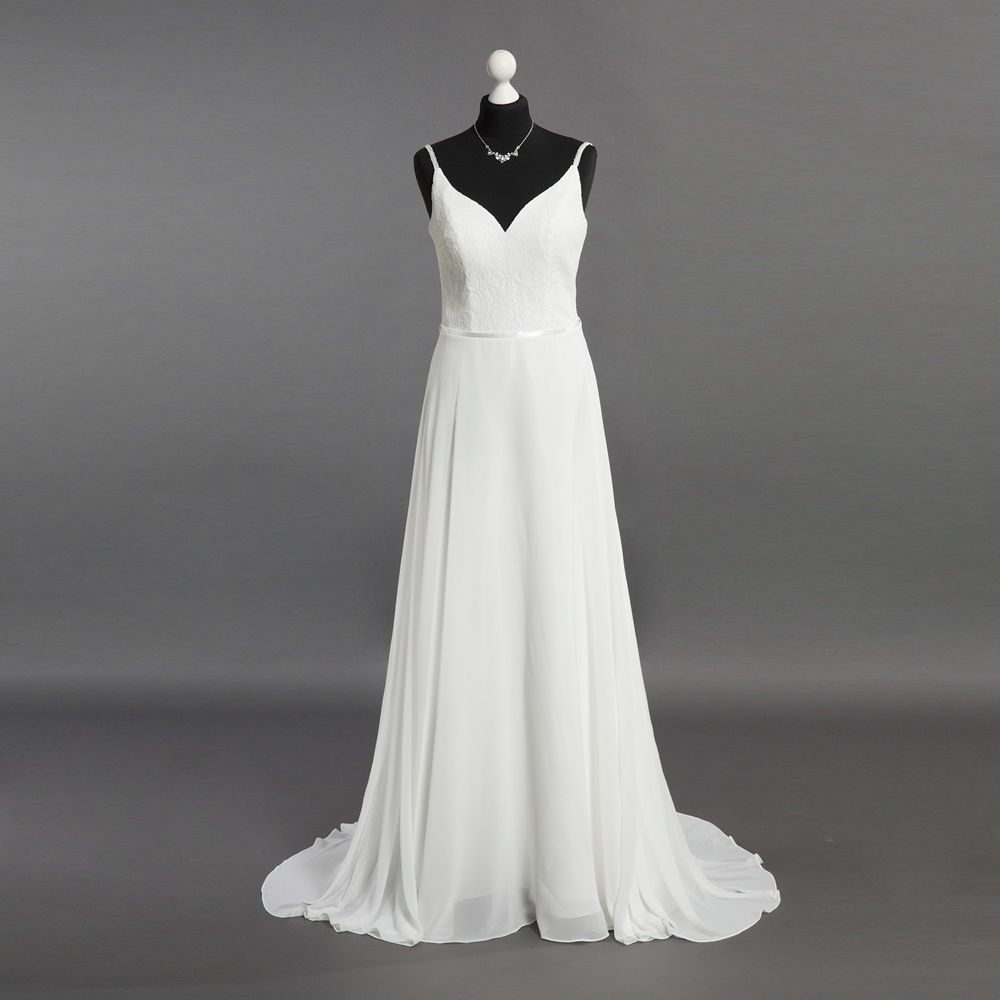 Ein weißes Brautkleid hängt auf einer Schaufensterpuppe vor einem grauen Hintergrund