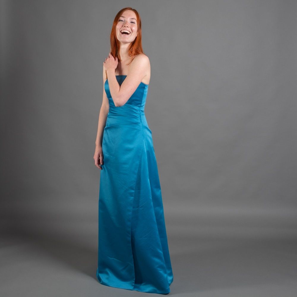 Eine Frau in einem blauen trägerlosen Kleid lächelt