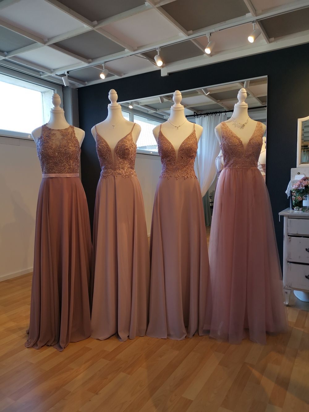 In einem Raum sind mehrere Brautjungfernkleider auf Schaufensterpuppen aufgereiht.