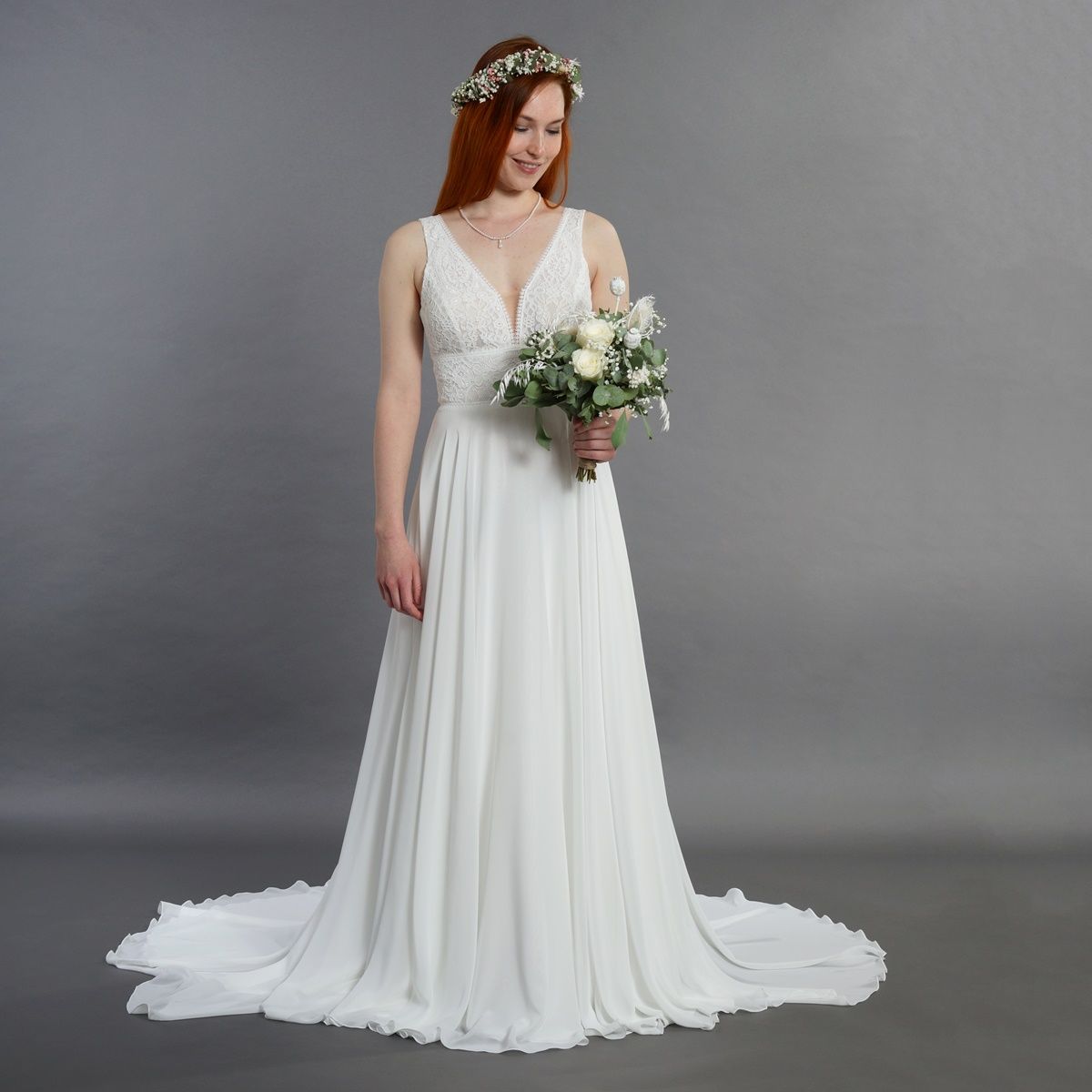 Eine Frau in einem weißen Brautkleid hält einen Blumenstrauß.