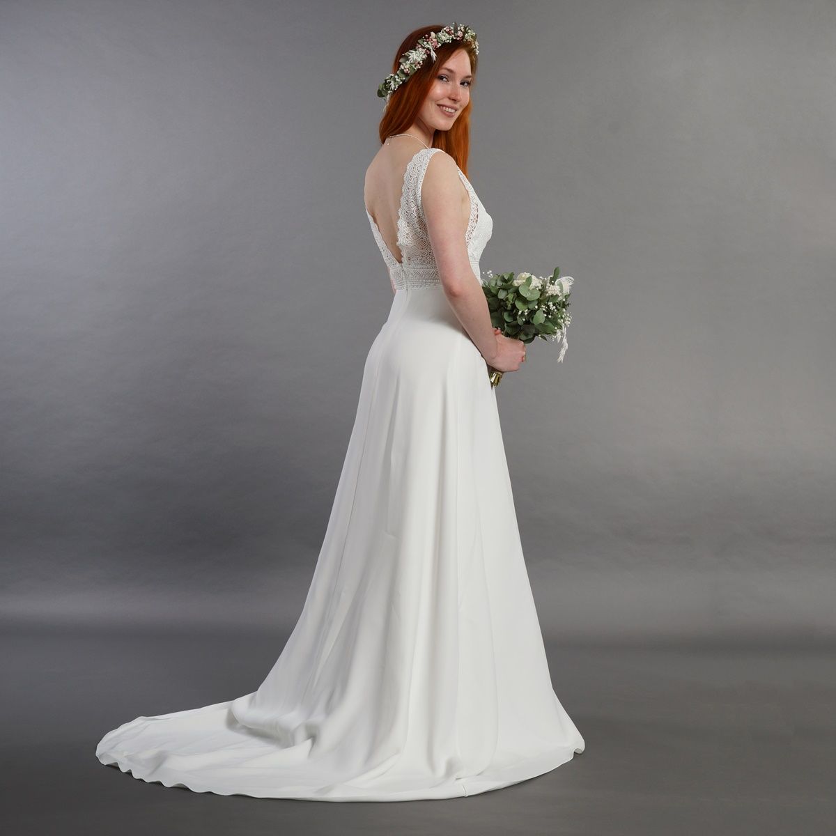 Eine Frau in einem weißen Brautkleid hält einen Blumenstrauß.