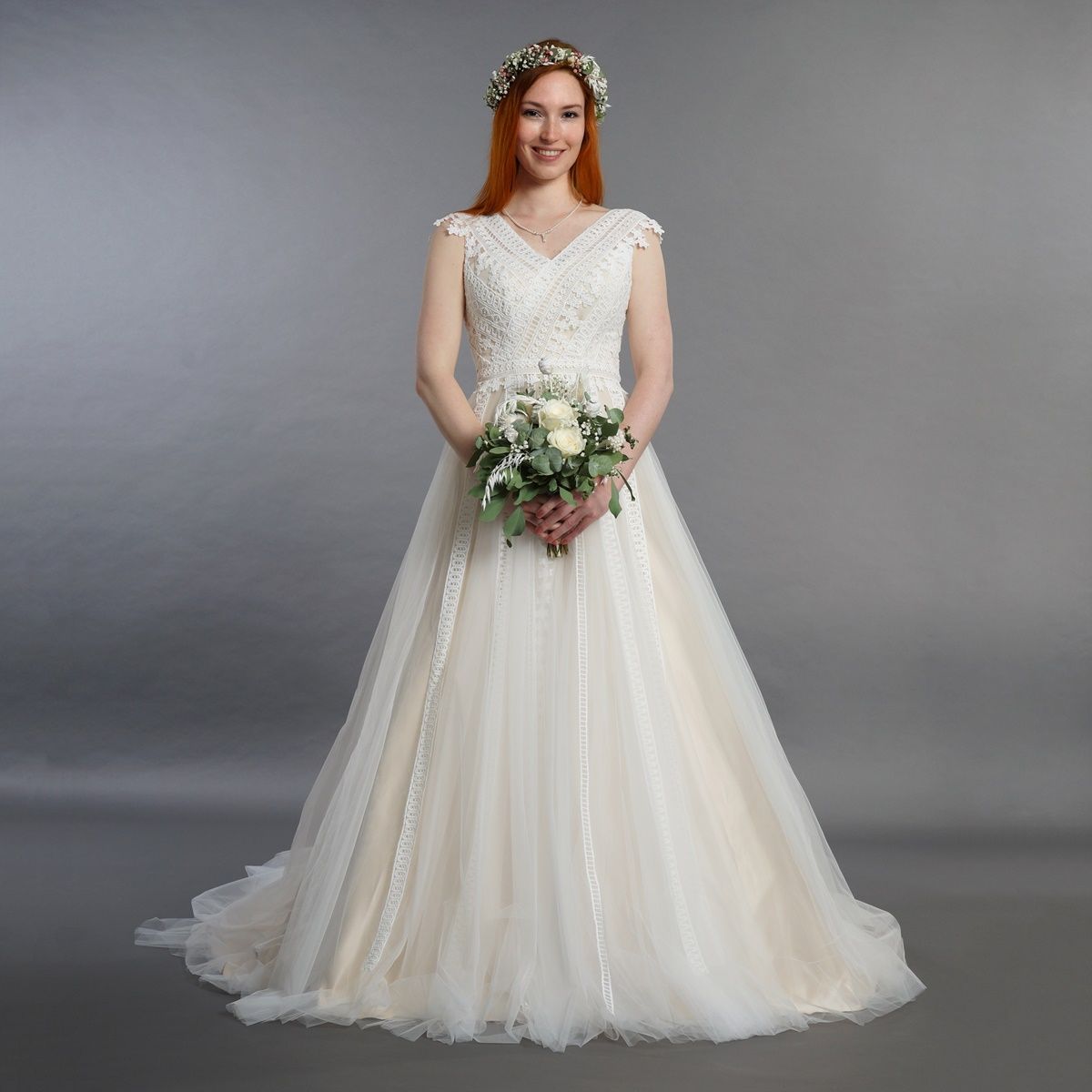 Eine Frau in einem Brautkleid hält einen Blumenstrauß.