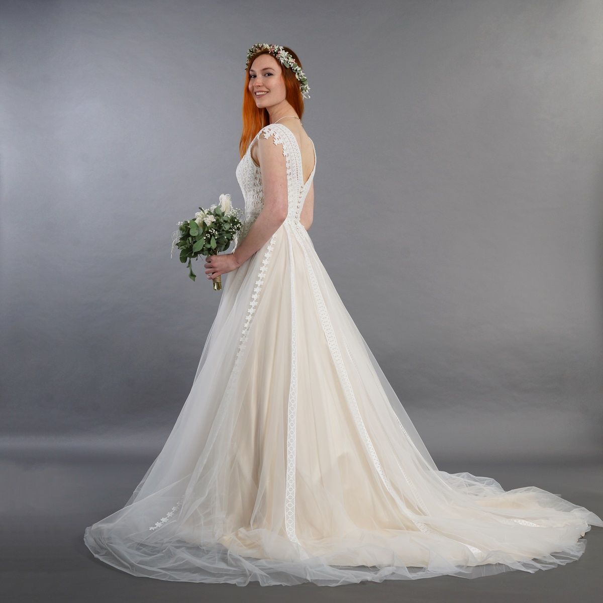 Eine Frau in einem Brautkleid hält einen Blumenstrauß.