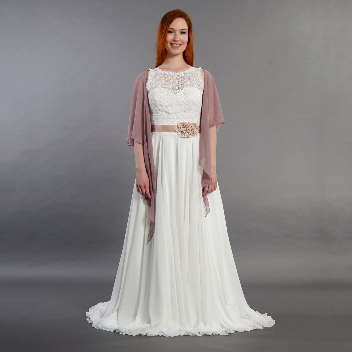 Eine Frau trägt ein weißes Brautkleid mit einem rosa Schal.