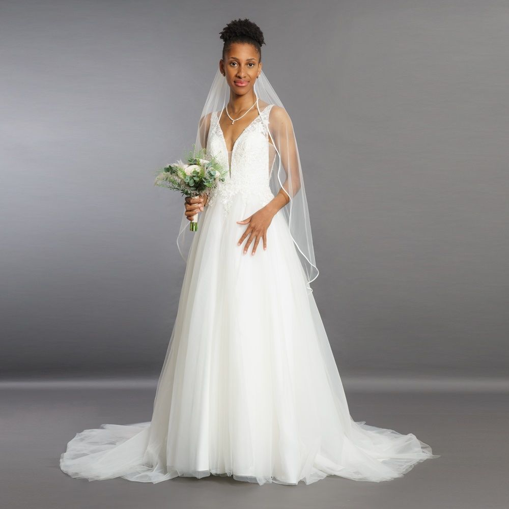 Eine Frau in einem Brautkleid hält einen Blumenstrauß.