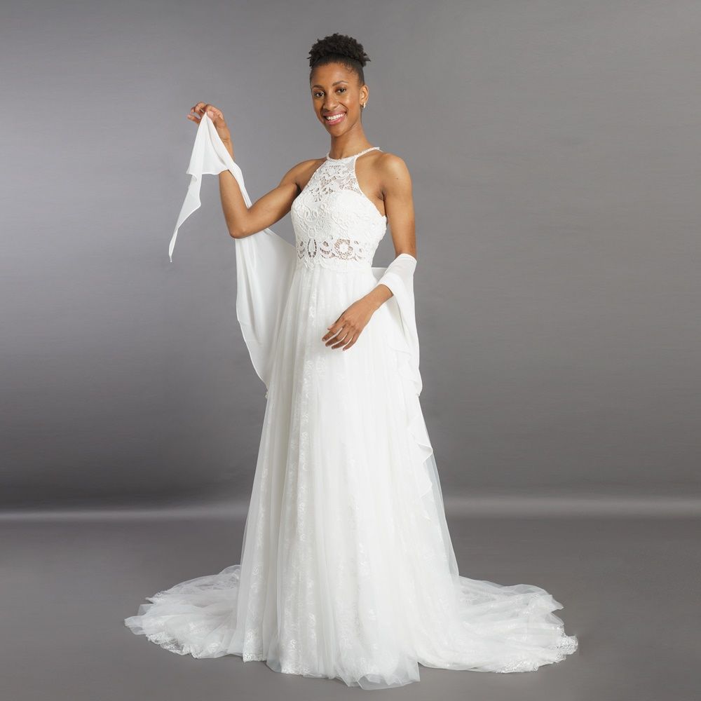 Eine Frau in einem weißen Brautkleid hält einen weißen Schal.