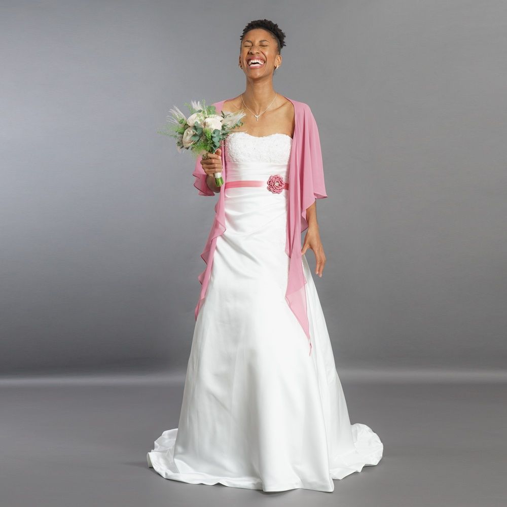 Eine Frau in einem weißen Brautkleid hält einen Blumenstrauß