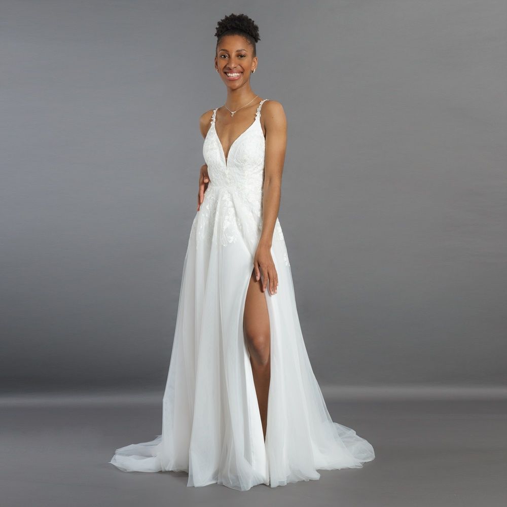 Eine Frau trägt ein weißes Brautkleid mit hohem Schlitz.