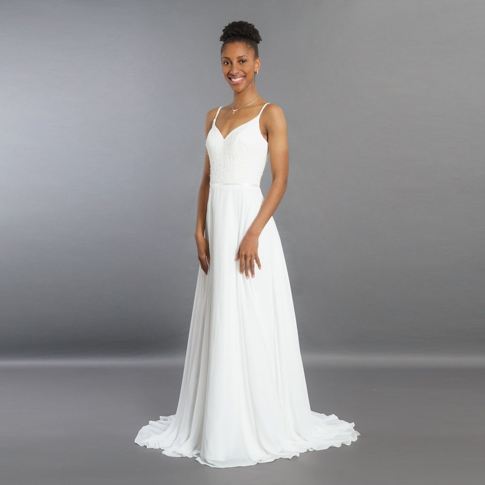 Eine Frau trägt ein weißes Brautkleid und lächelt