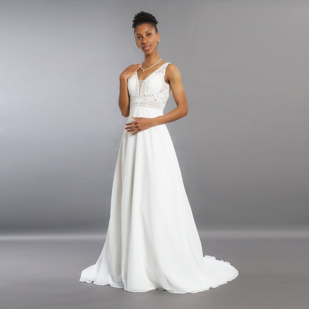 Eine Frau in einem weißen Brautkleid steht auf einem grauen Hintergrund