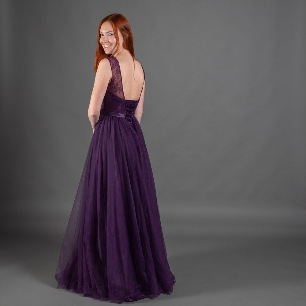 Zu sehen ist der Rücken einer Frau in einem lila Kleid.