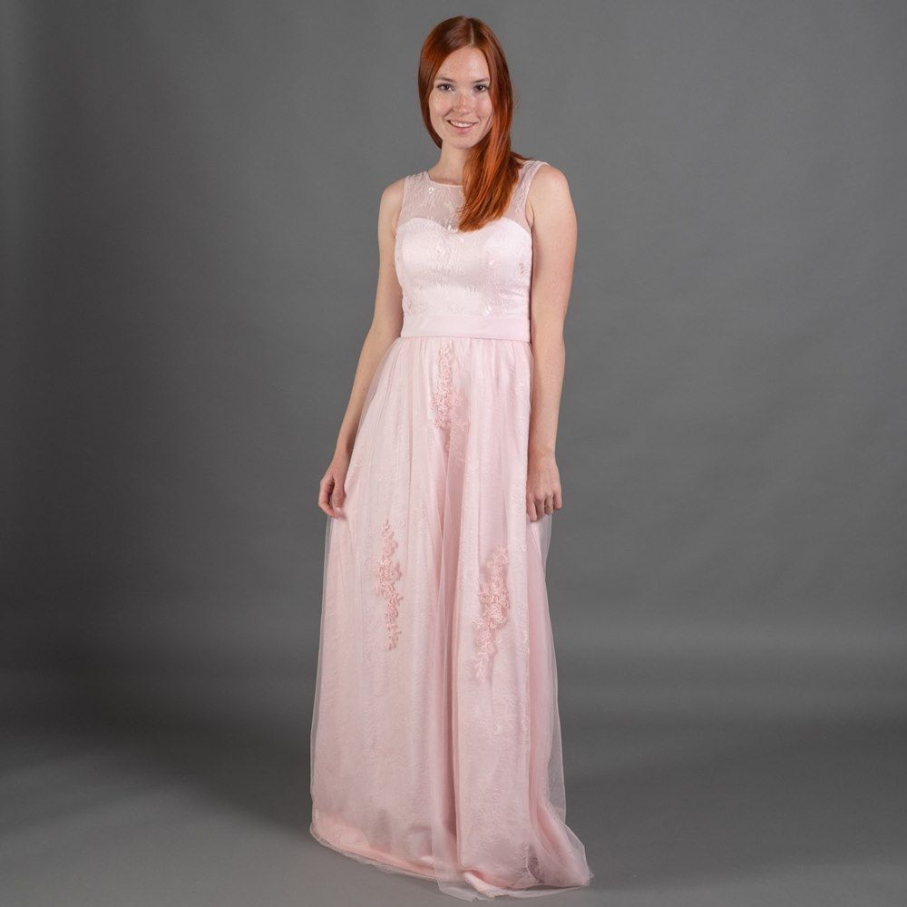 Eine Frau trägt ein langes rosa Kleid und lächelt.