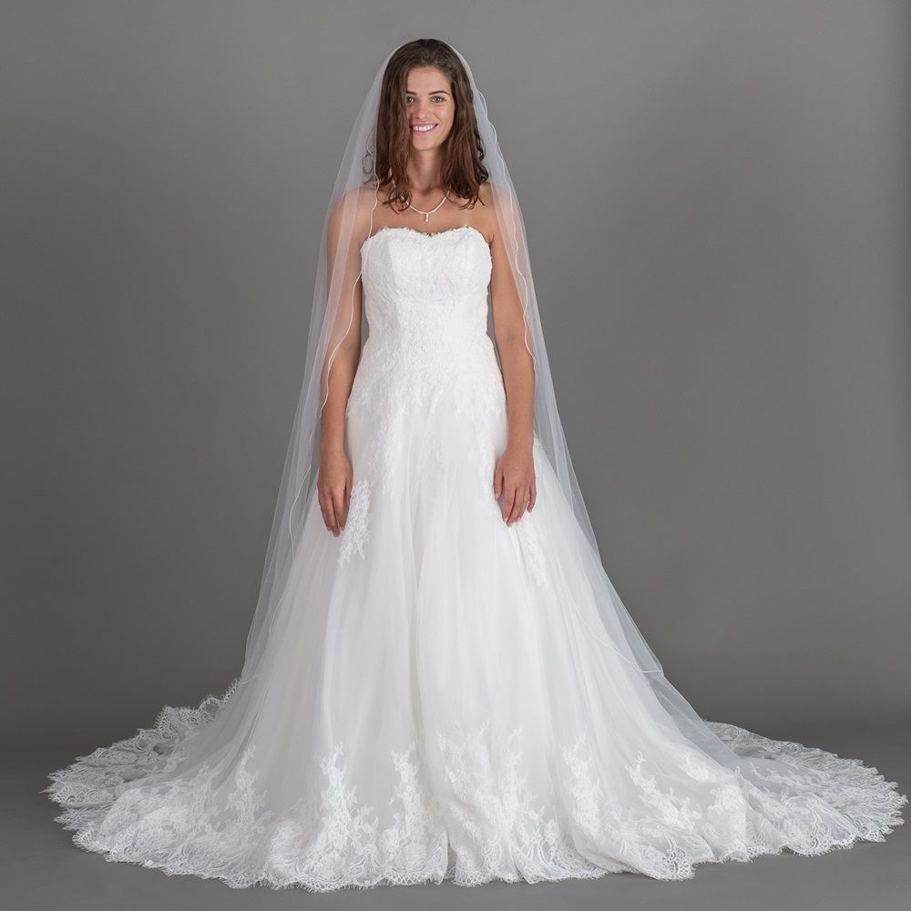 Eine Frau trägt ein weißes Brautkleid und einen Schleier.