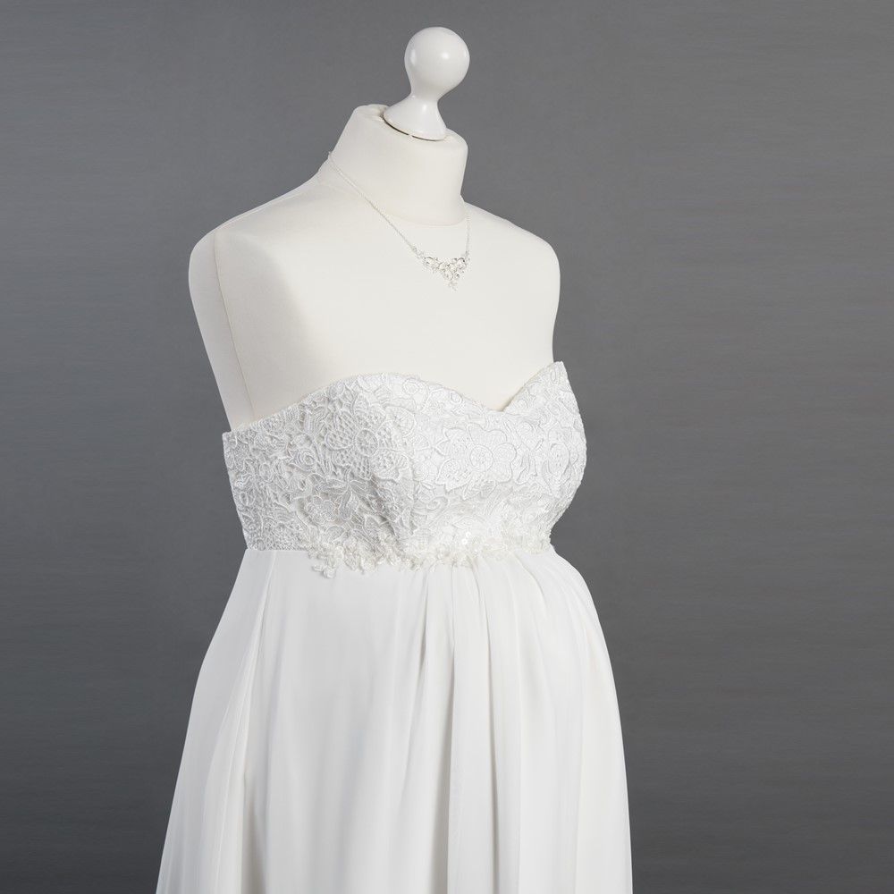 Ein weißes Kleid hängt an einer Schaufensterpuppe mit einer Halskette