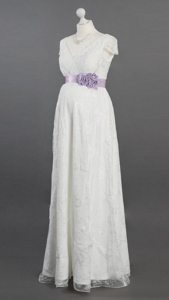 Auf einer Schaufensterpuppe hängt ein weißes Brautkleid mit einer violetten Schärpe.