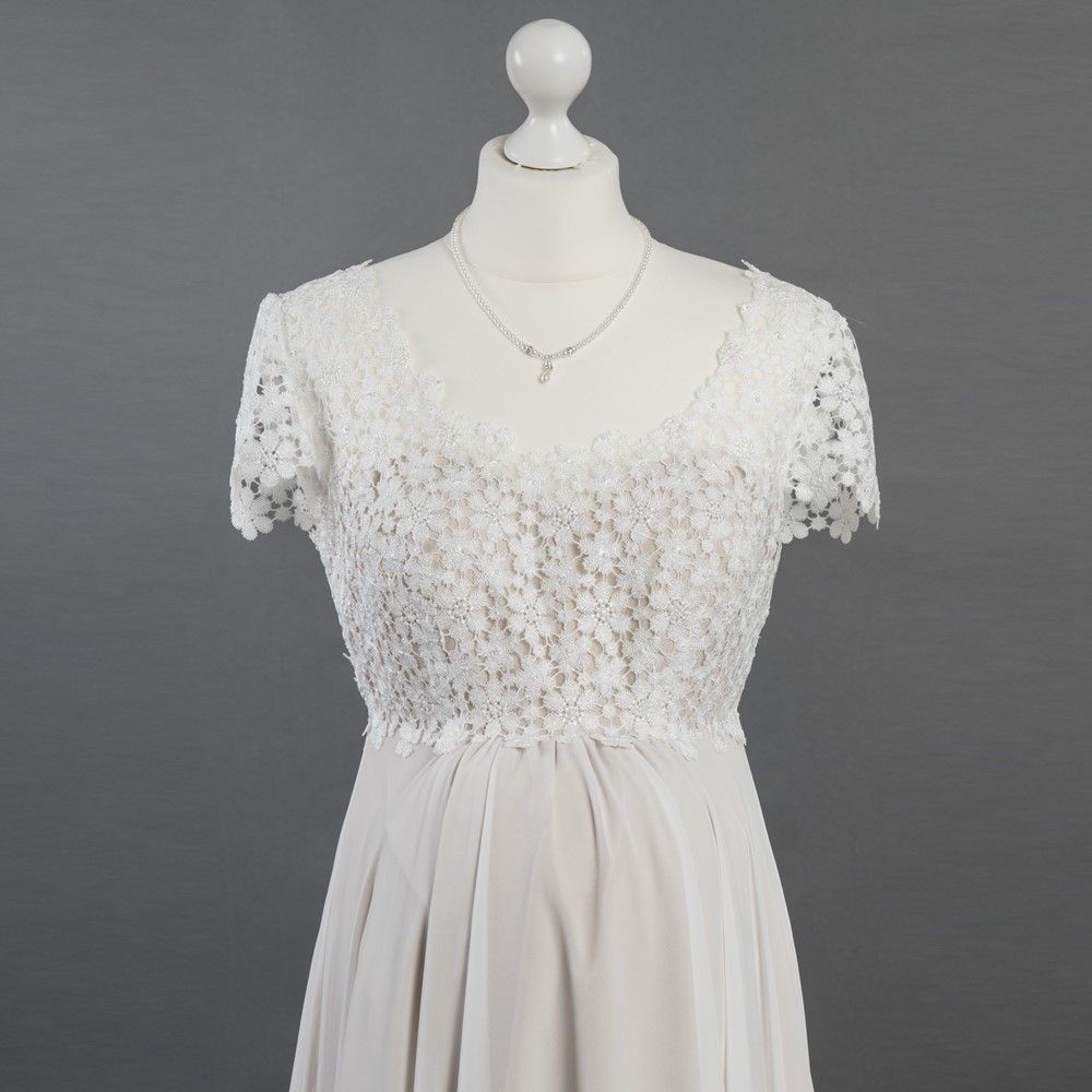 Ein weißes Spitzenkleid mit kurzen Ärmeln ist auf einer Schaufensterpuppe