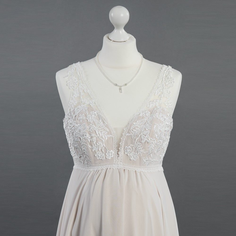 Eine Schaufensterpuppe, die ein weißes Spitzenkleid und eine Halskette trägt