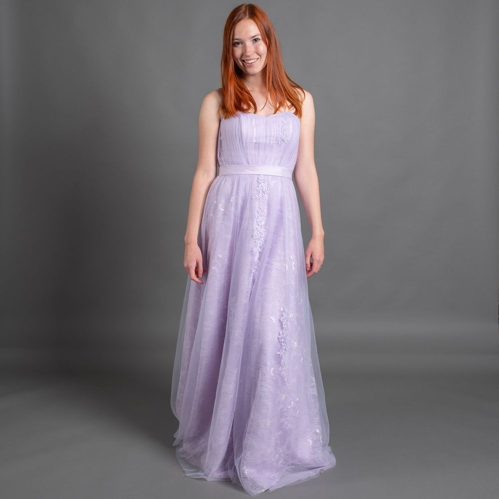 Eine Frau trägt ein lila Kleid und lächelt.