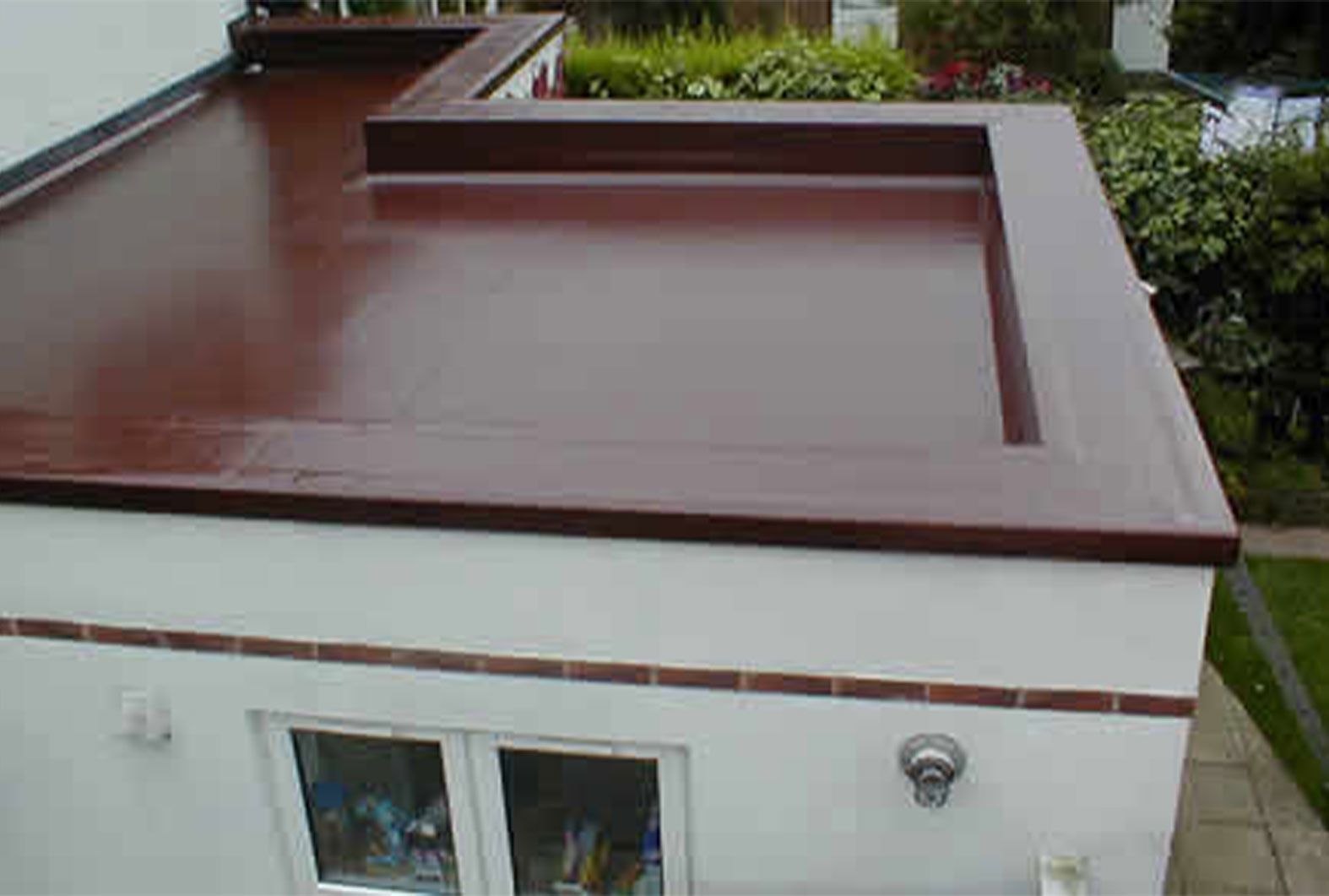 A white building with a brown roof and two windows.