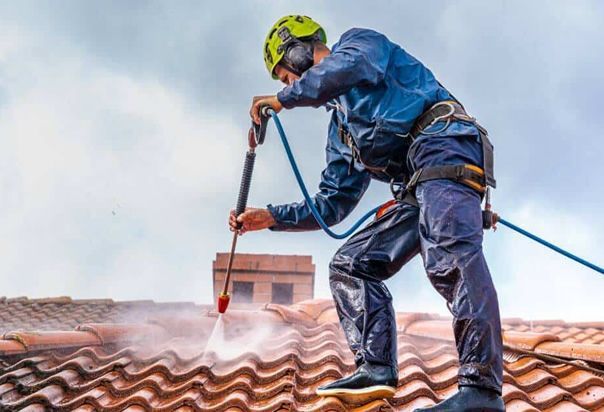 A man is cleaning a tiled roof with a high pressure washer.