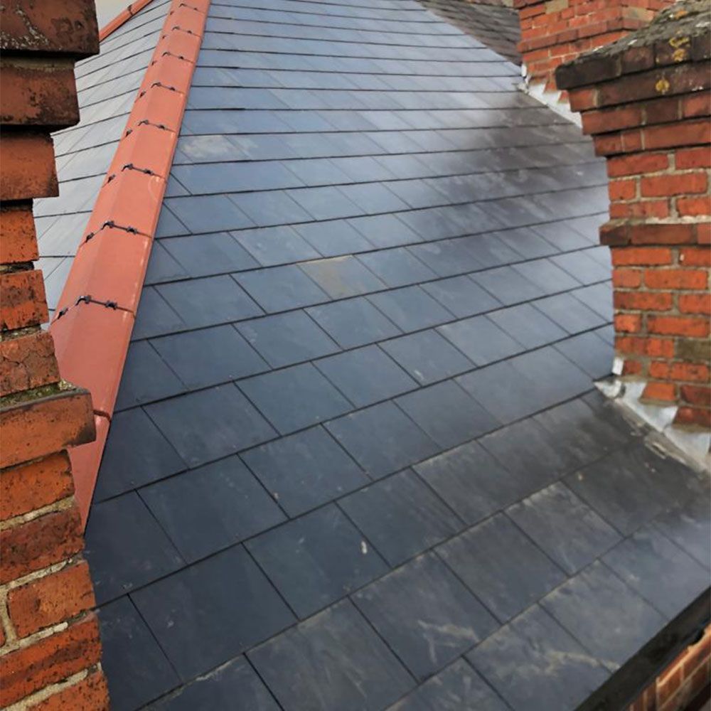 A roof with a brick chimney on the side of it