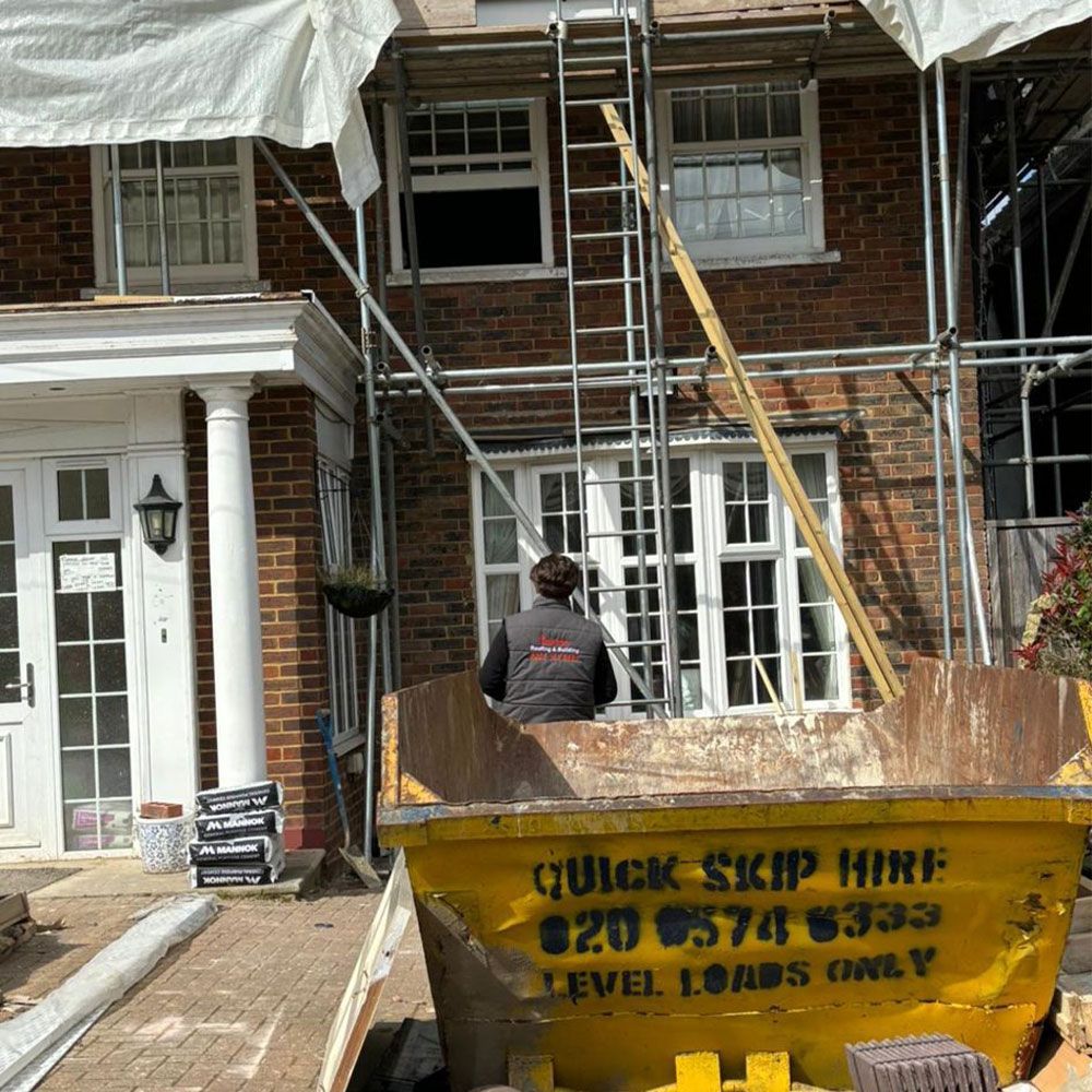 A man is standing next to a yellow dumpster that says quick skip hire