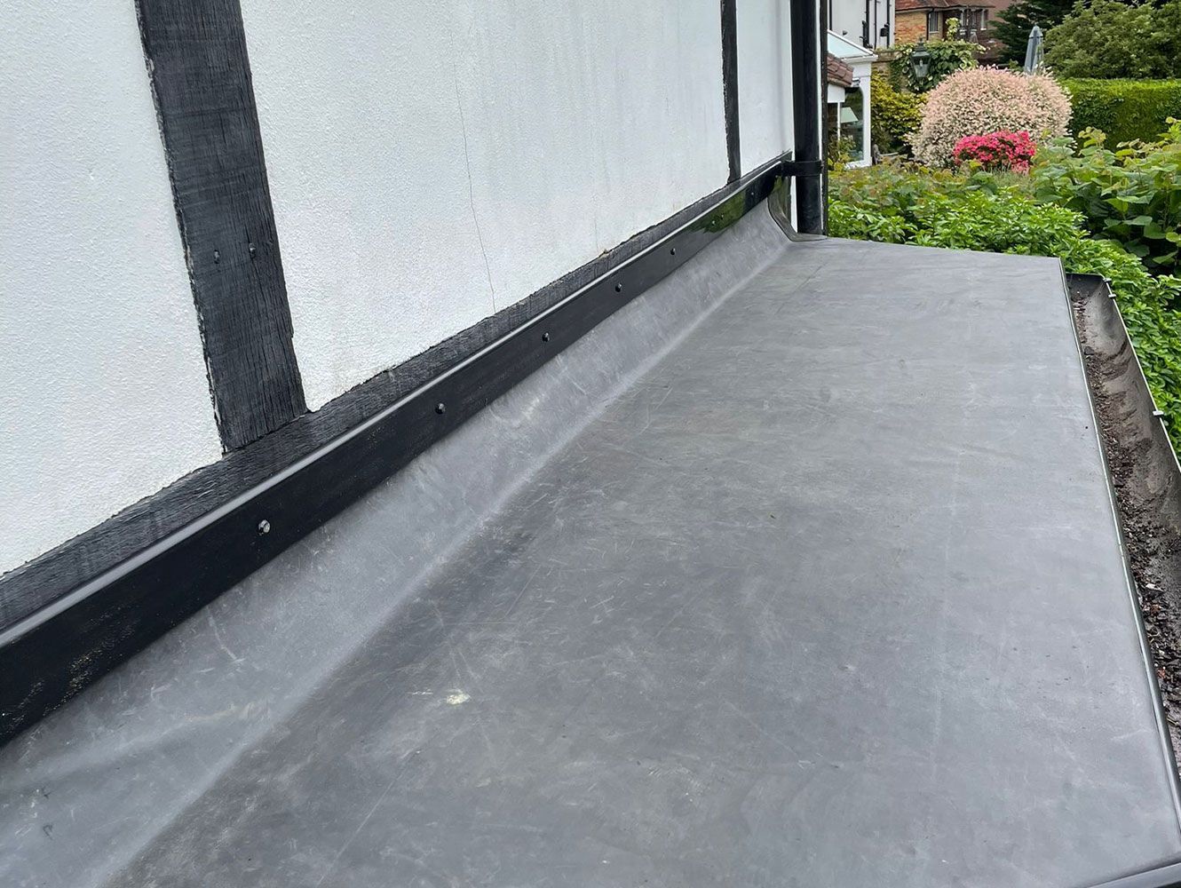 A black and white building with a black gutter on the side of it.