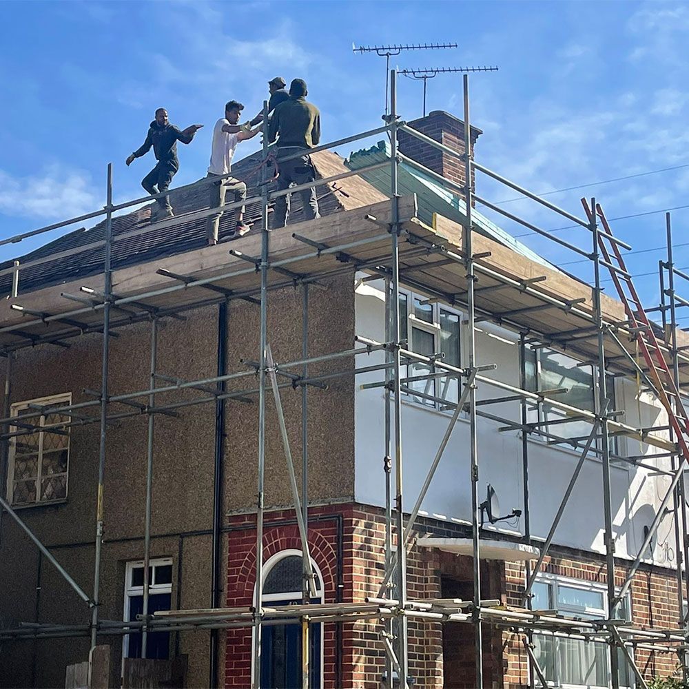 A group of people are working on the roof of a house.