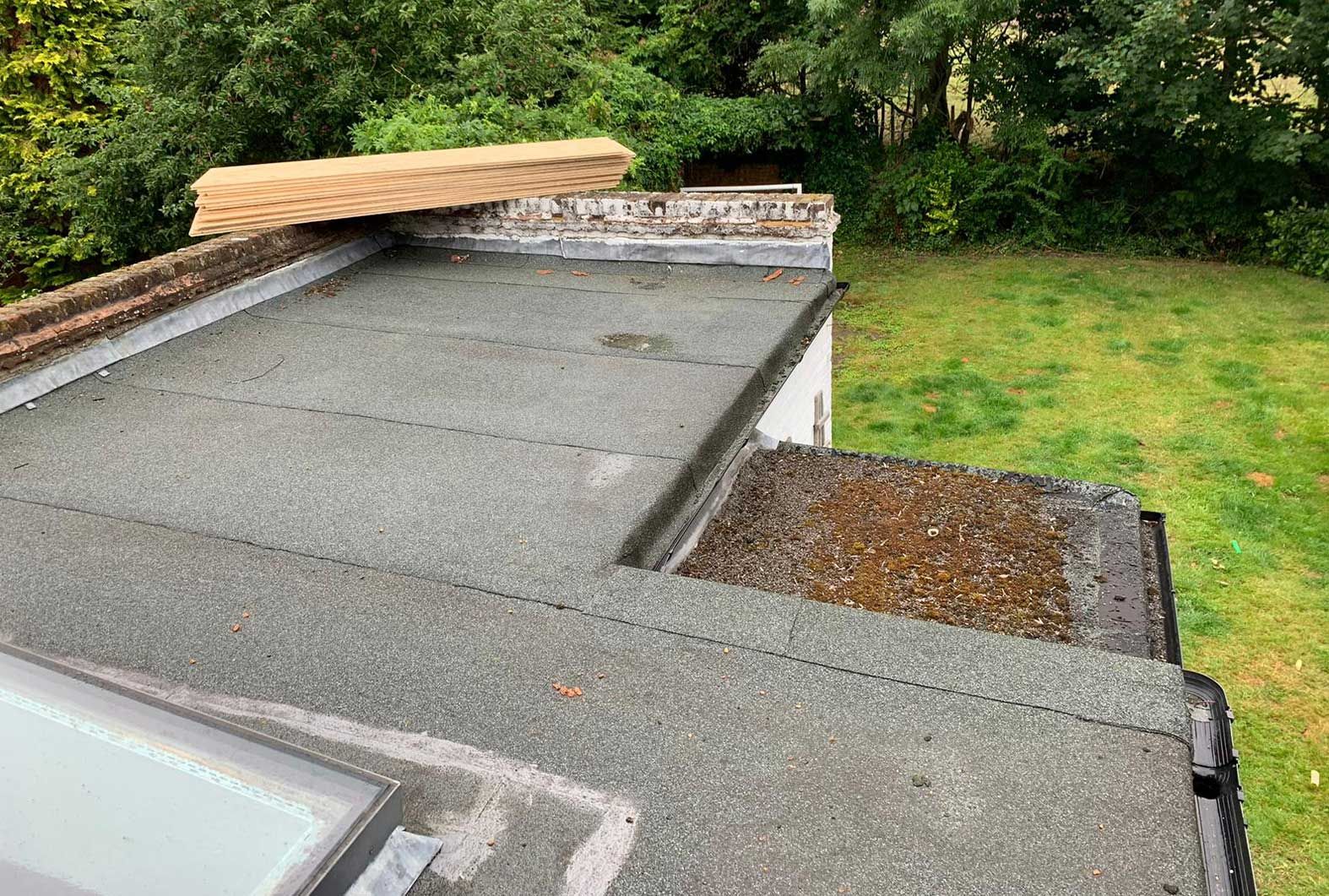 A roof with a skylight and a piece of wood on top of it.