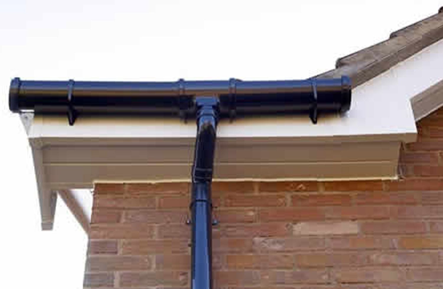 A black gutter is on the side of a brick building.