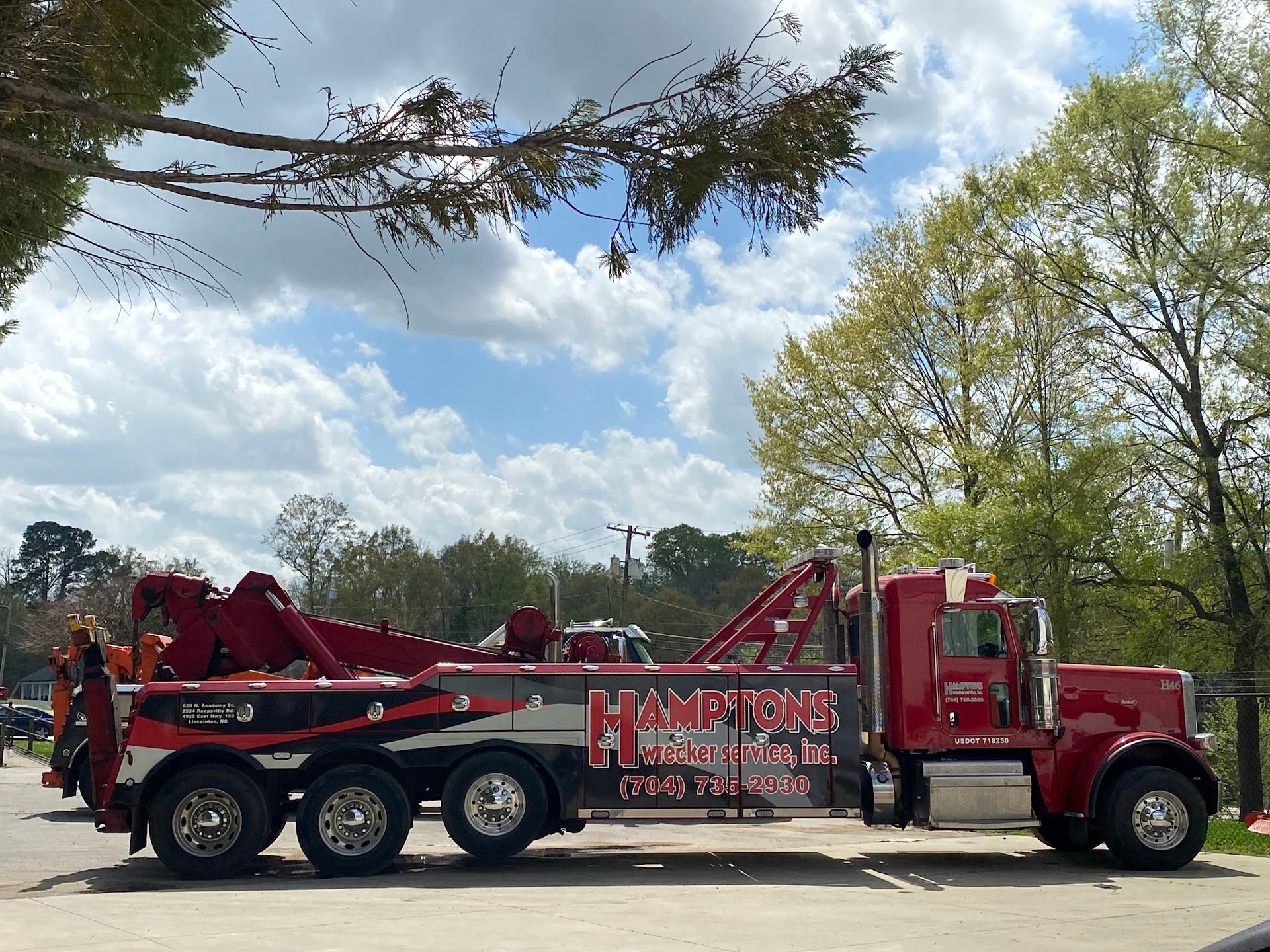 A red tow truck parked on a paved area with 