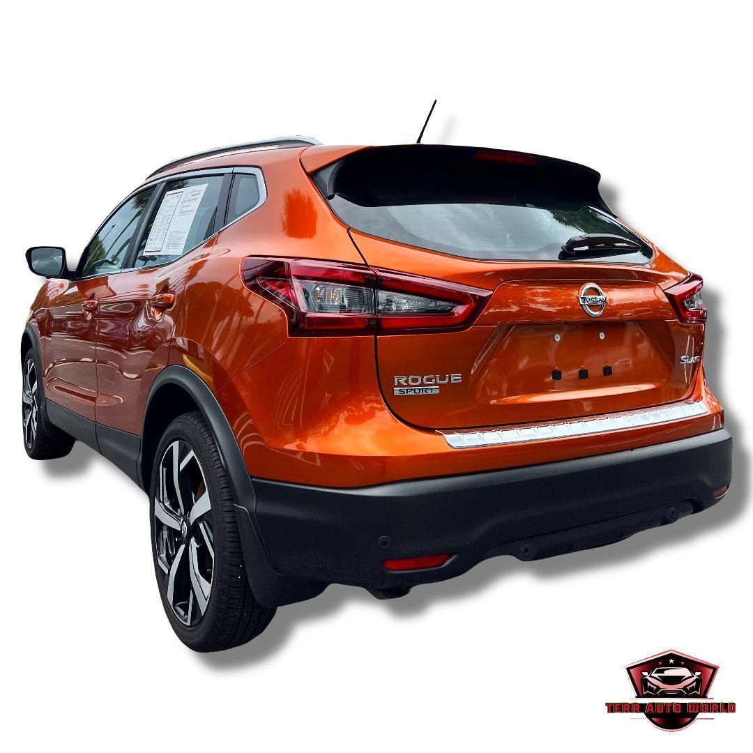 A bright orange Nissan Rogue SUV viewed from the rear three-quarter angle against a white background.