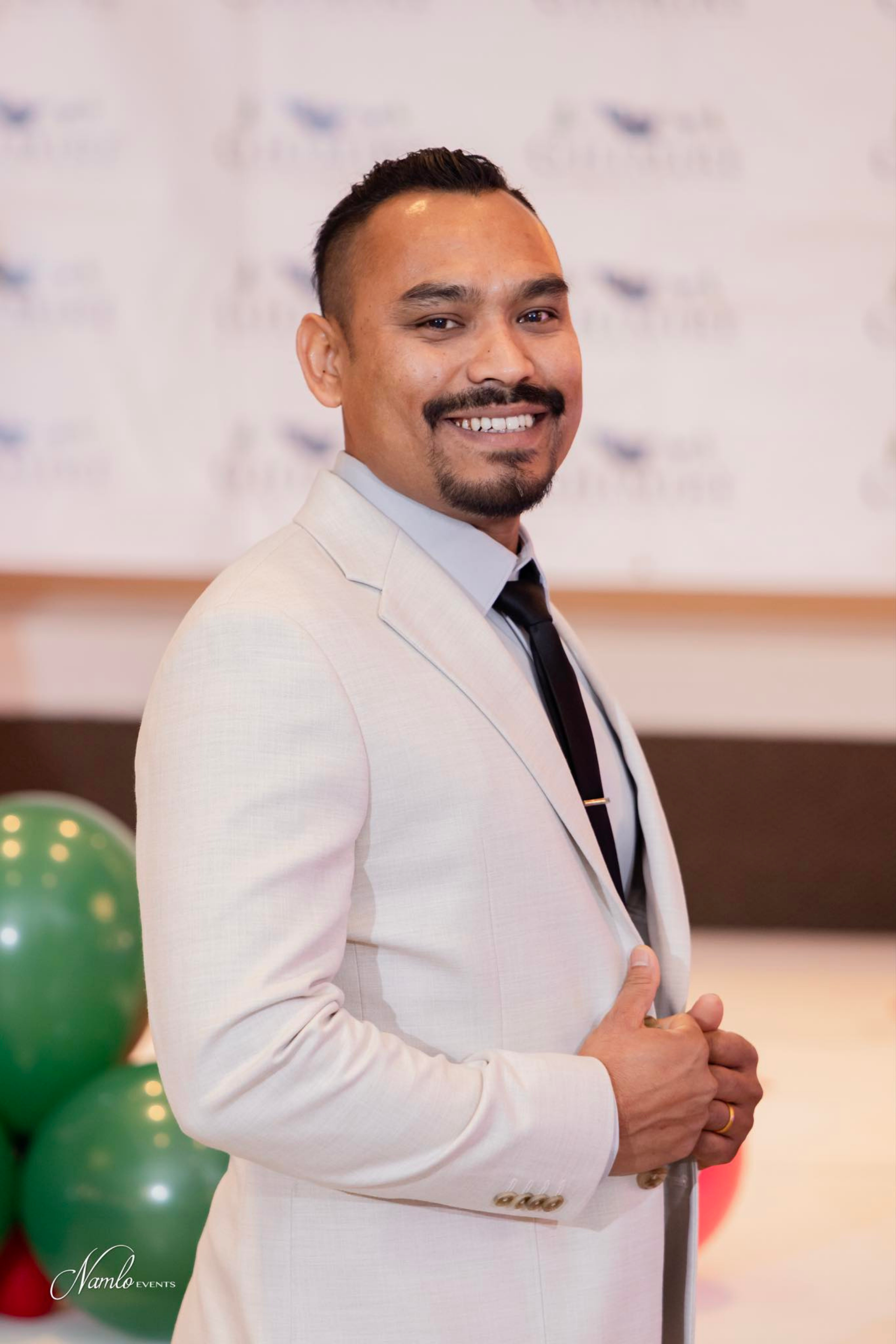 A woman is sitting at a desk with a laptop and a vase of flowers.