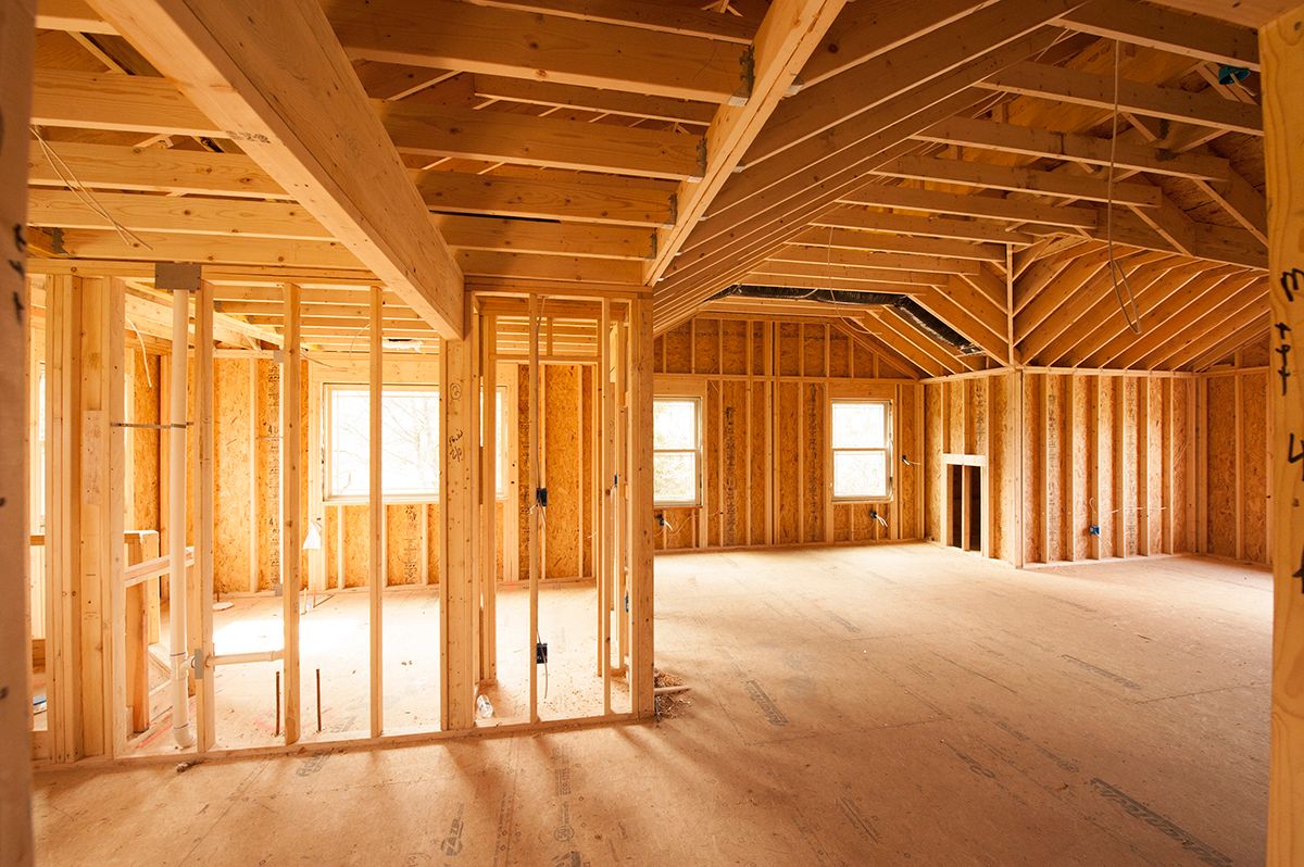 Interior view of a house under construction with exposed wooden beams, walls, and flooring.