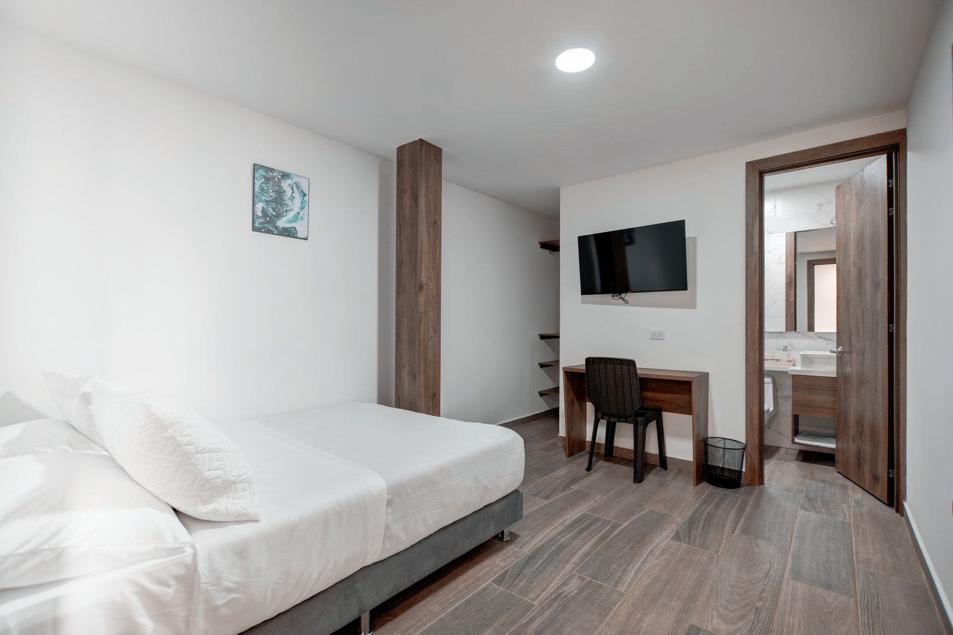 Un dormitorio con cama, escritorio, silla y puerta.