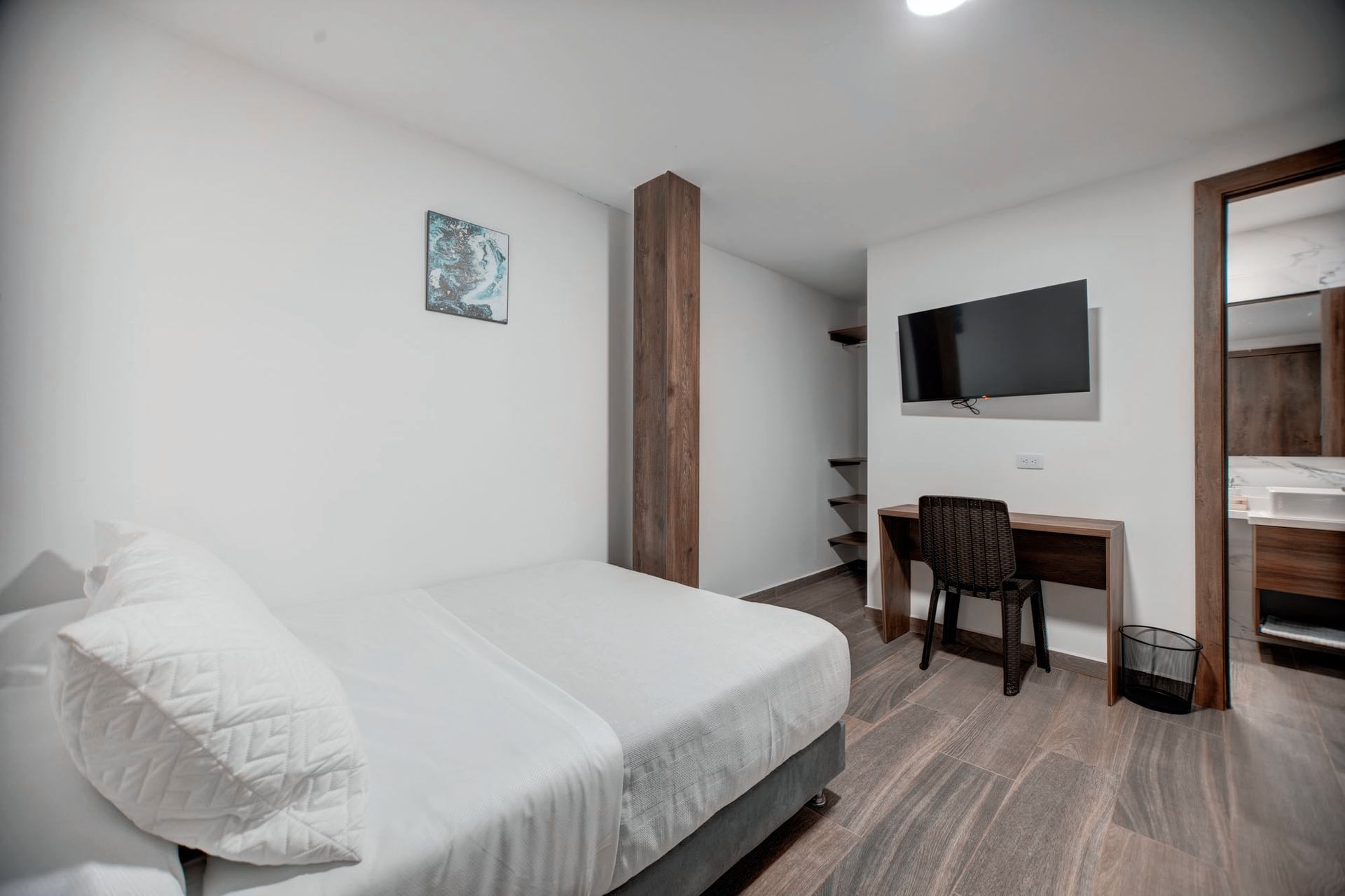 Una habitación de hotel con cama, escritorio, silla y televisión.