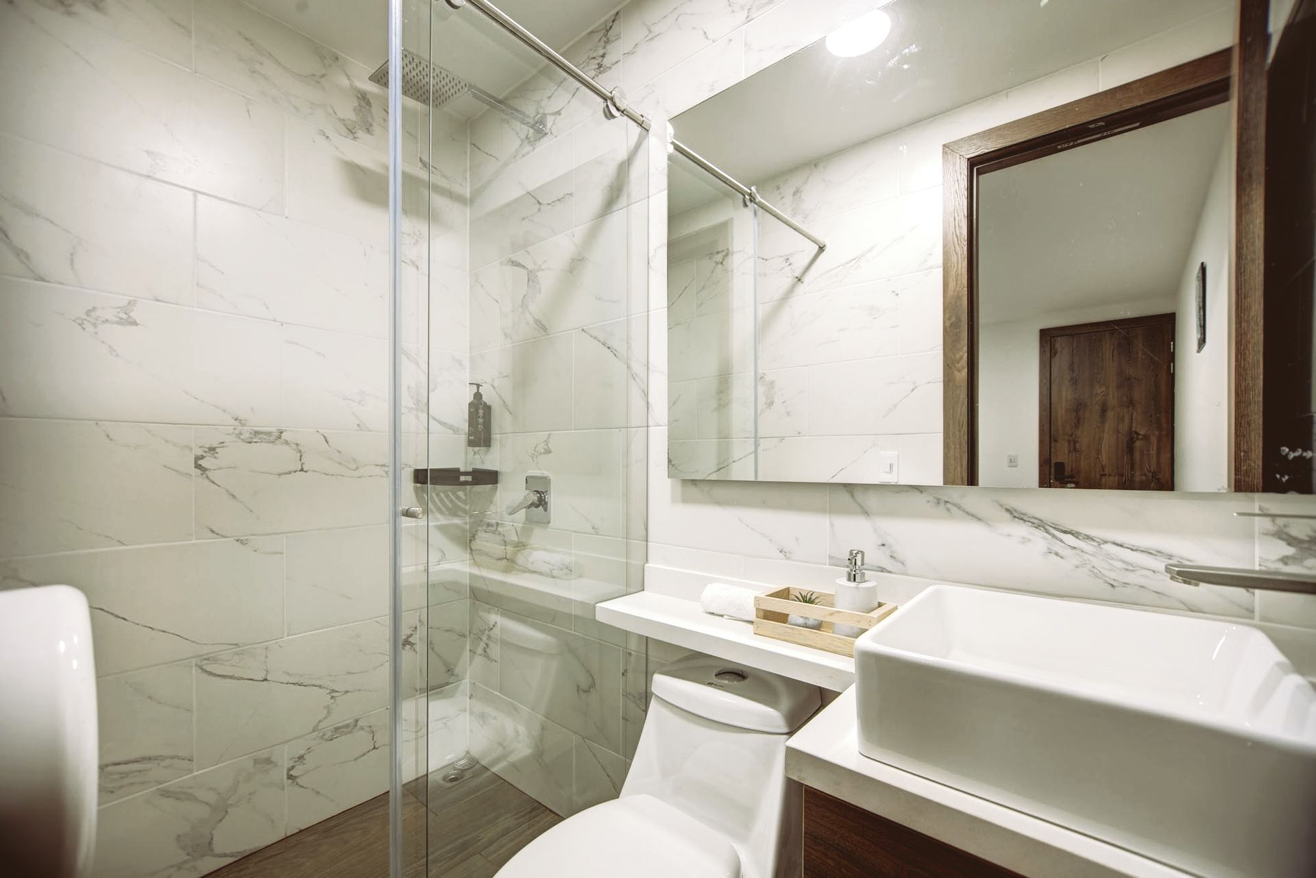 Un baño con inodoro, lavabo, espejo y ducha.