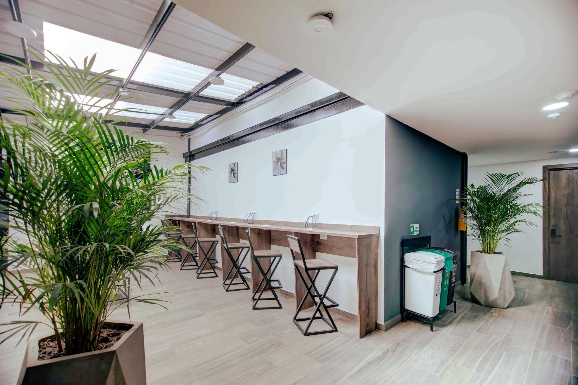 Una sala con mesas y sillas y plantas en macetas.