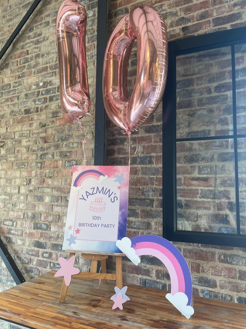 A wooden table with balloons and a rainbow on it.