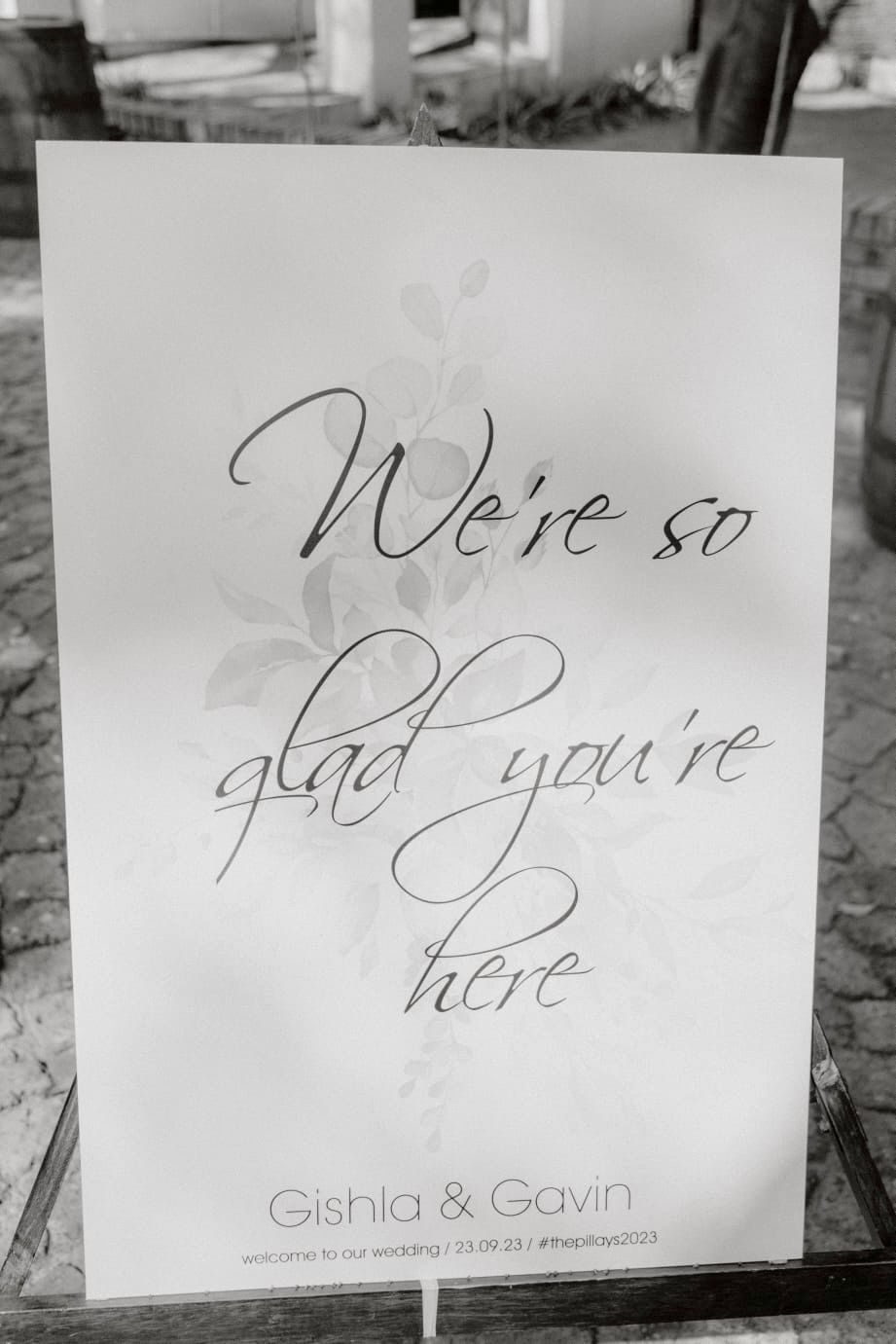 A black and white photo of a sign that says `` we 're so glad you 're here ''.