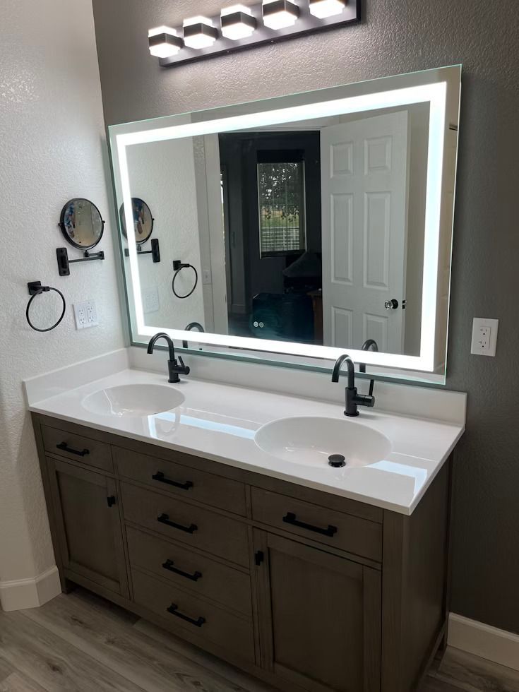wide mirror with white sinks and brown cupboard