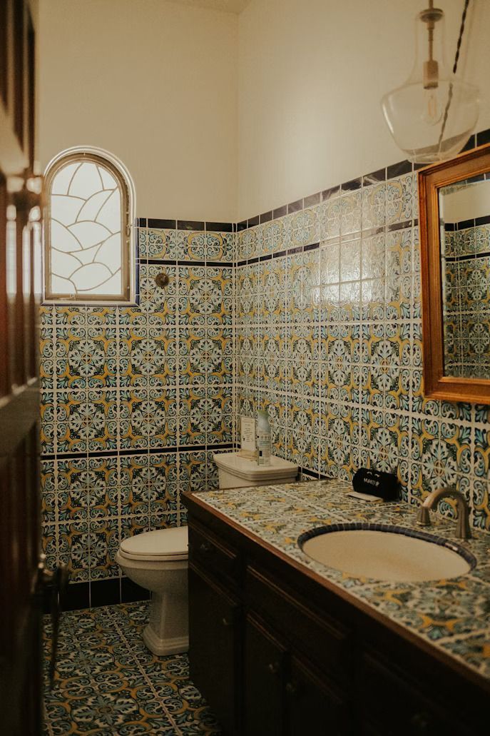 traditional bathroom style with toilet and patterned wall and floor tiles, along with patterned mirror