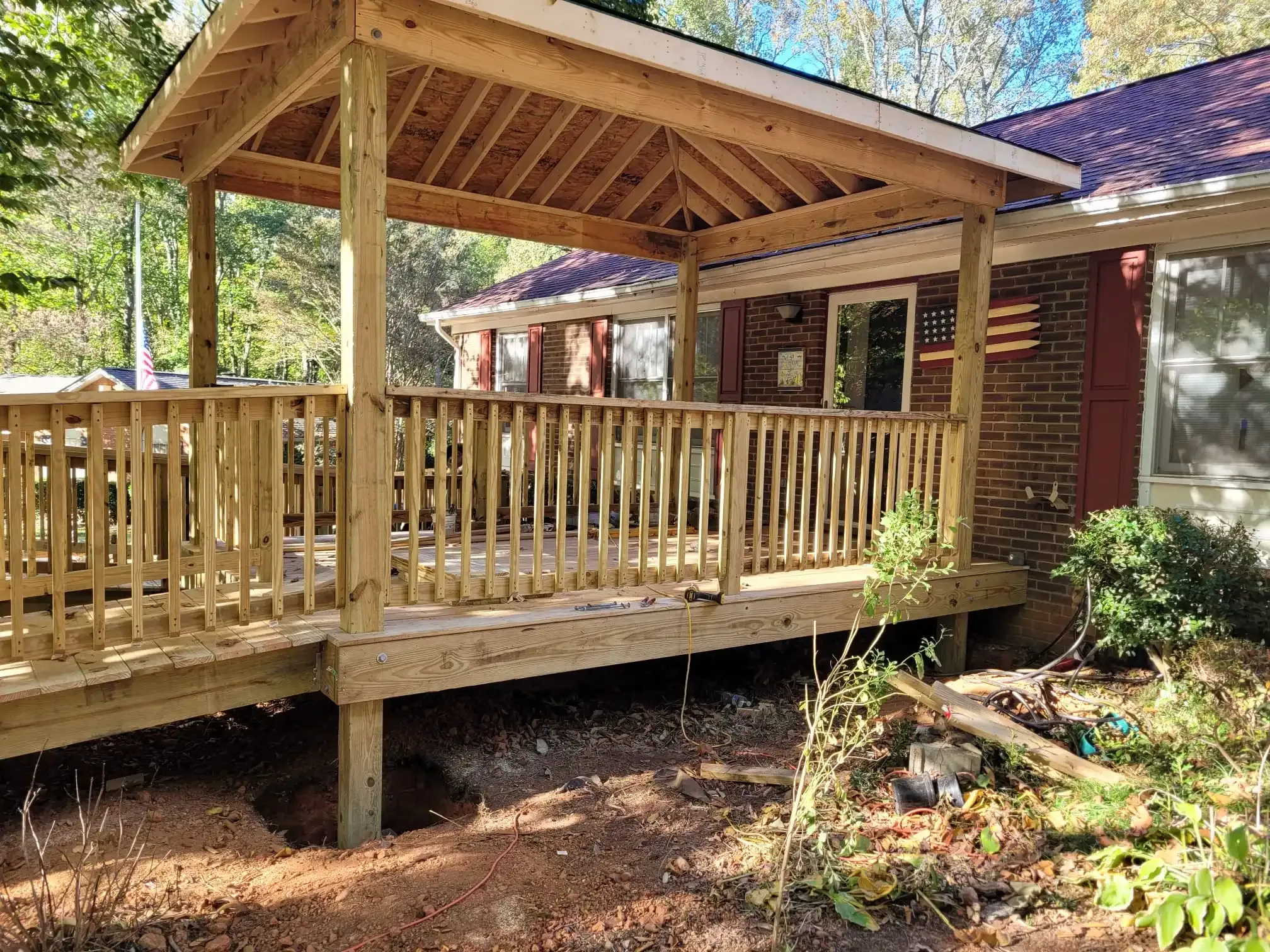 A wooden deck with a gazebo attached to it is in front of a house.