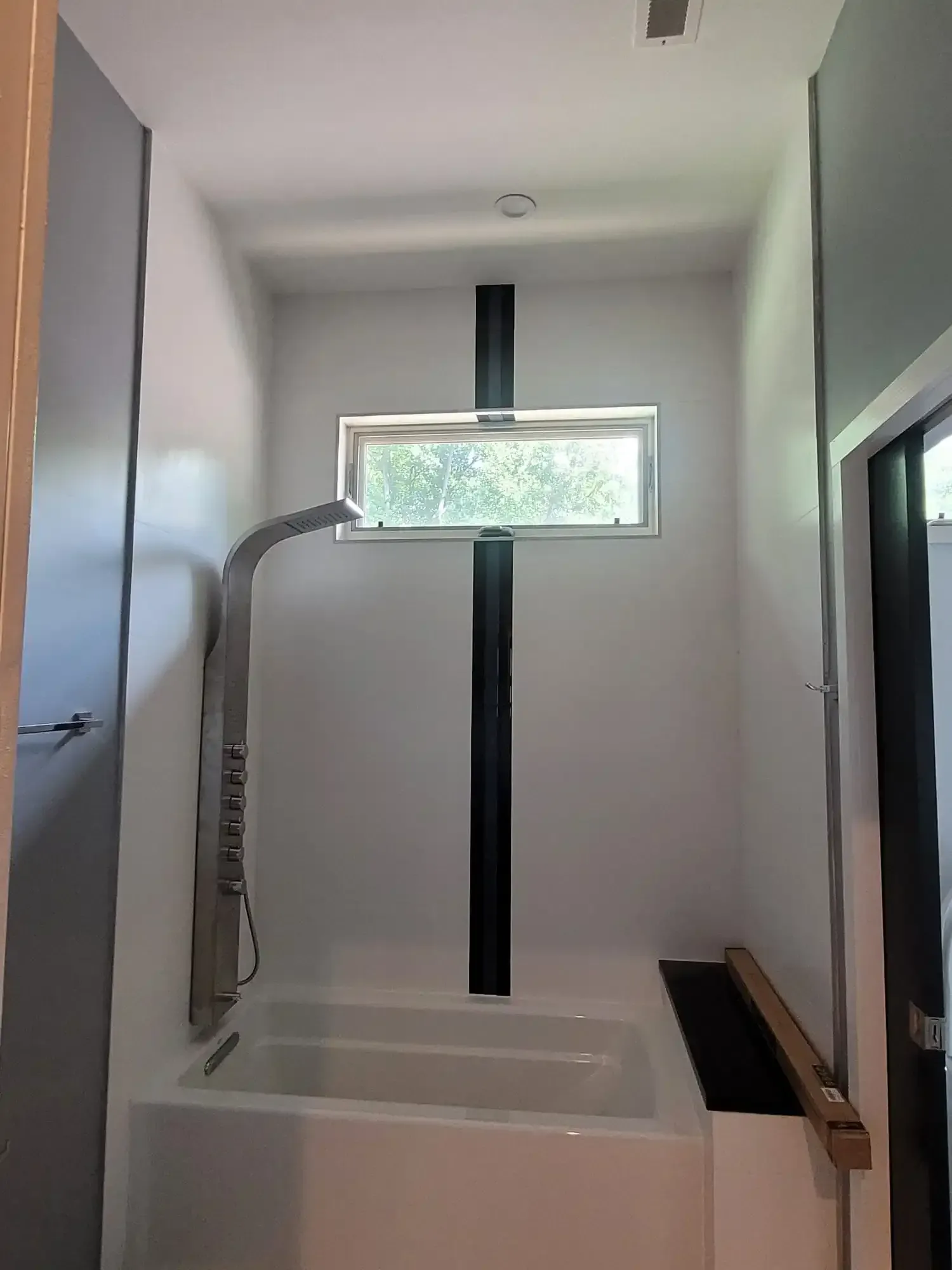 A bathroom with a tub , shower , and window.