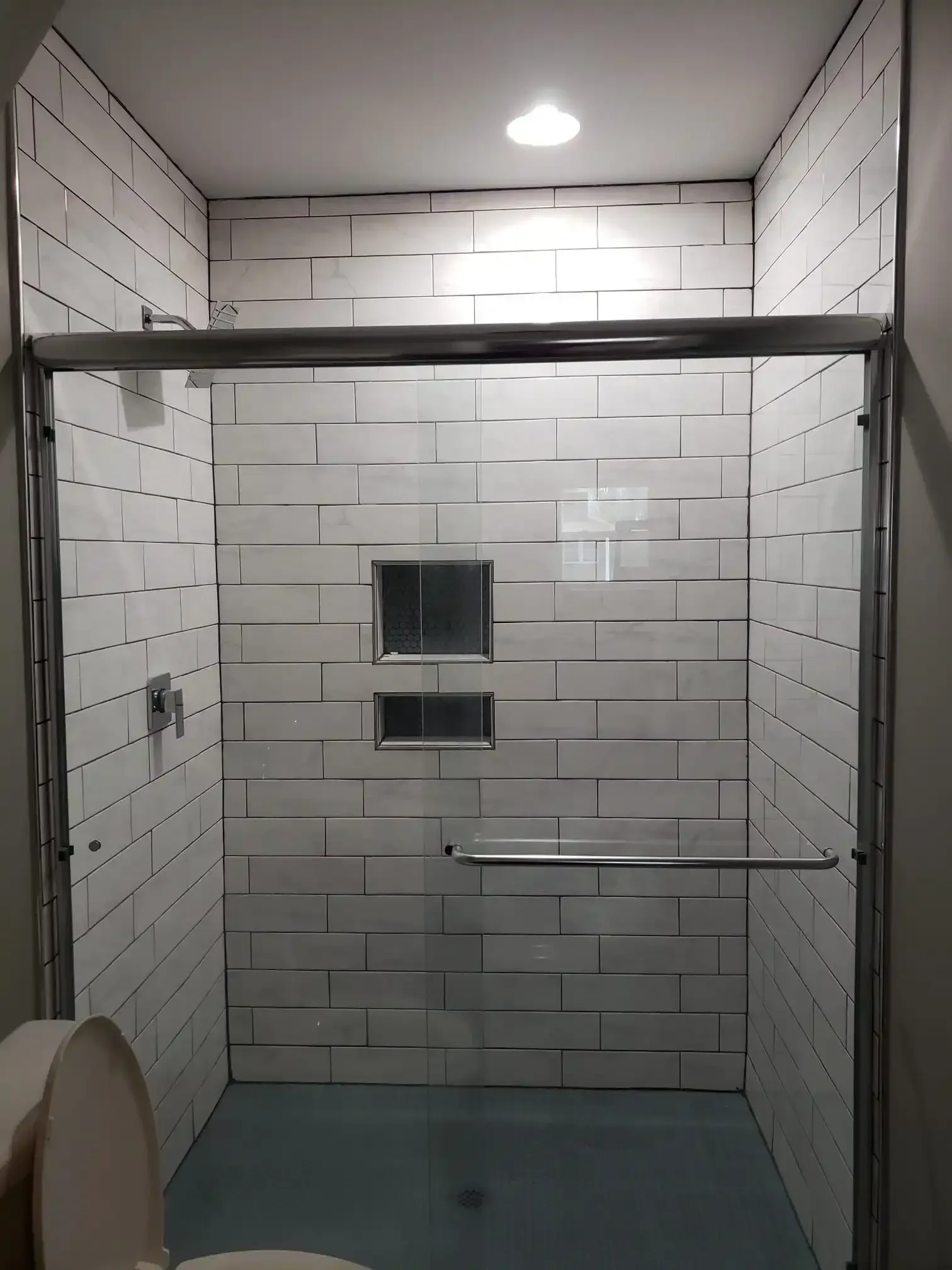 A bathroom with a toilet and a shower with a sliding glass door.