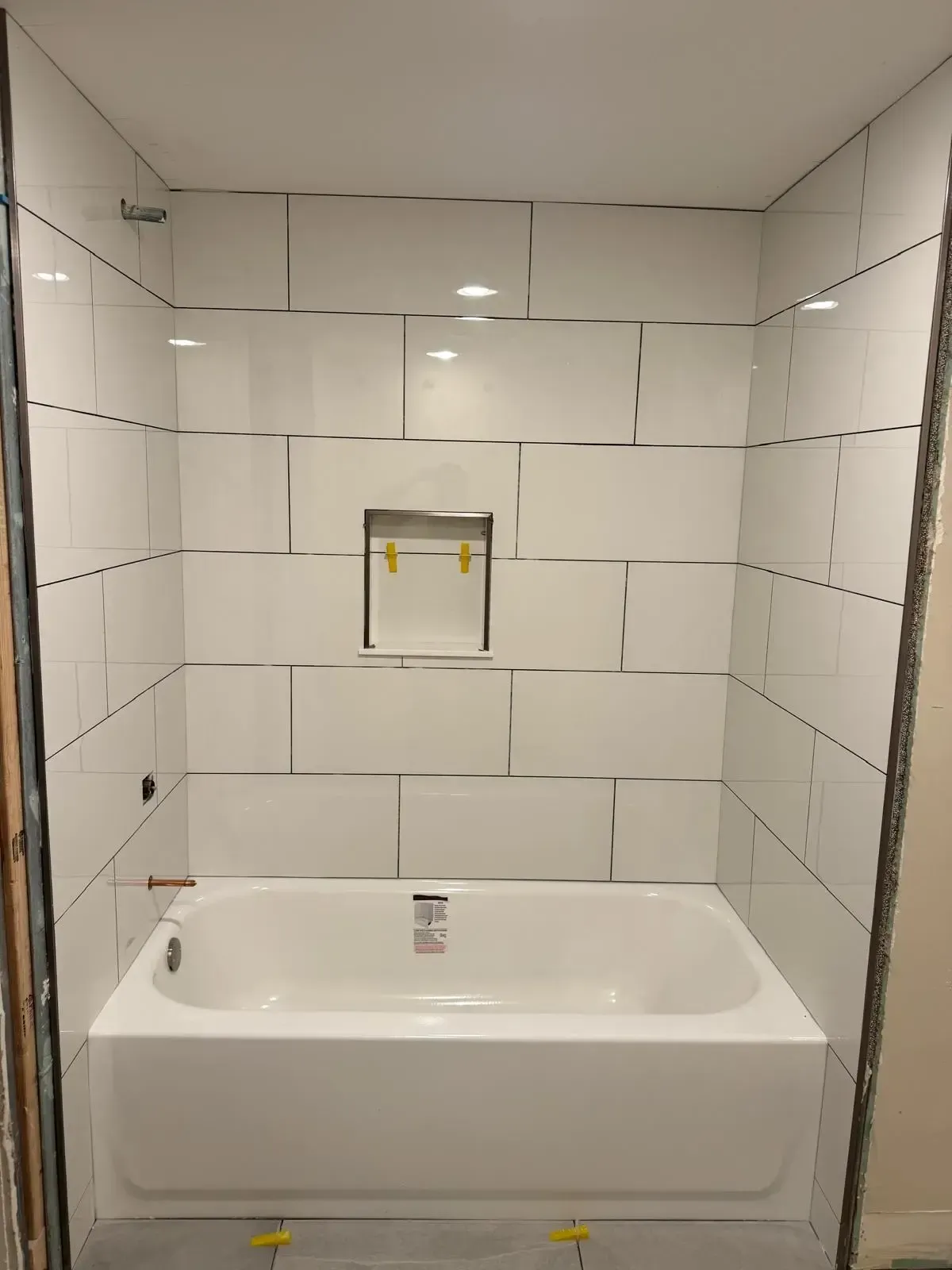 A bathtub is sitting in a bathroom with white tiles.