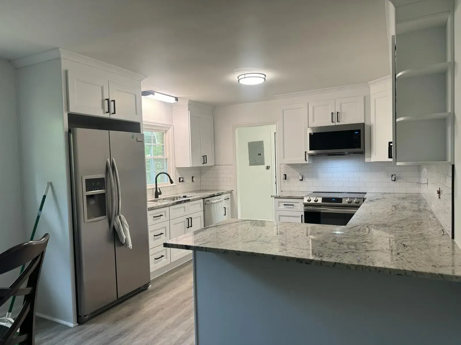 A kitchen with white cabinets , stainless steel appliances and granite counter tops.