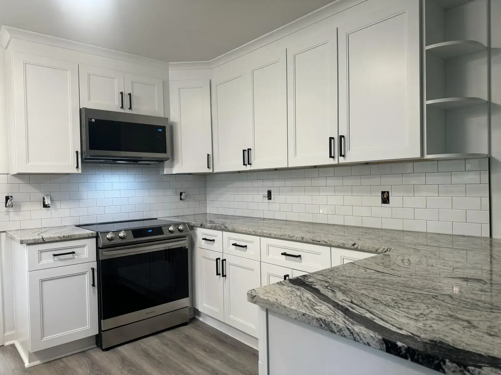 A kitchen with white cabinets , stainless steel appliances and granite counter tops.